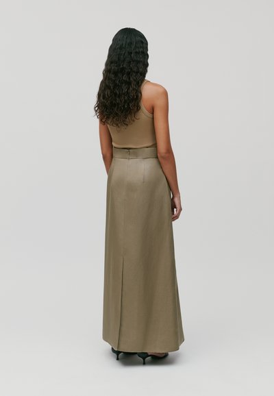 Gonna maxi khaki con spacco posteriore, silhouette sartoriale e dettaglio in vita. Indossata con un top beige aderente, mostrata da dietro.