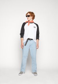 Raglan sleeve shirt with black sleeves and a white body, light blue jeans, black and white checkered shoes, and an orange bandana.