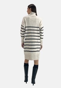 Knie-langes Turtleneck-Strickkleid in Creme mit schwarzen horizontalen Streifen. Rippbündchen und -säume, aus weichem Strickmaterial gefertigt.