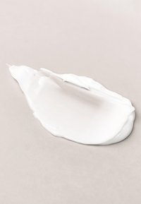 Zachte witte crème uitgesmeerd met een spatel op een lichte ondergrond, met zicht op textuur en dikte.