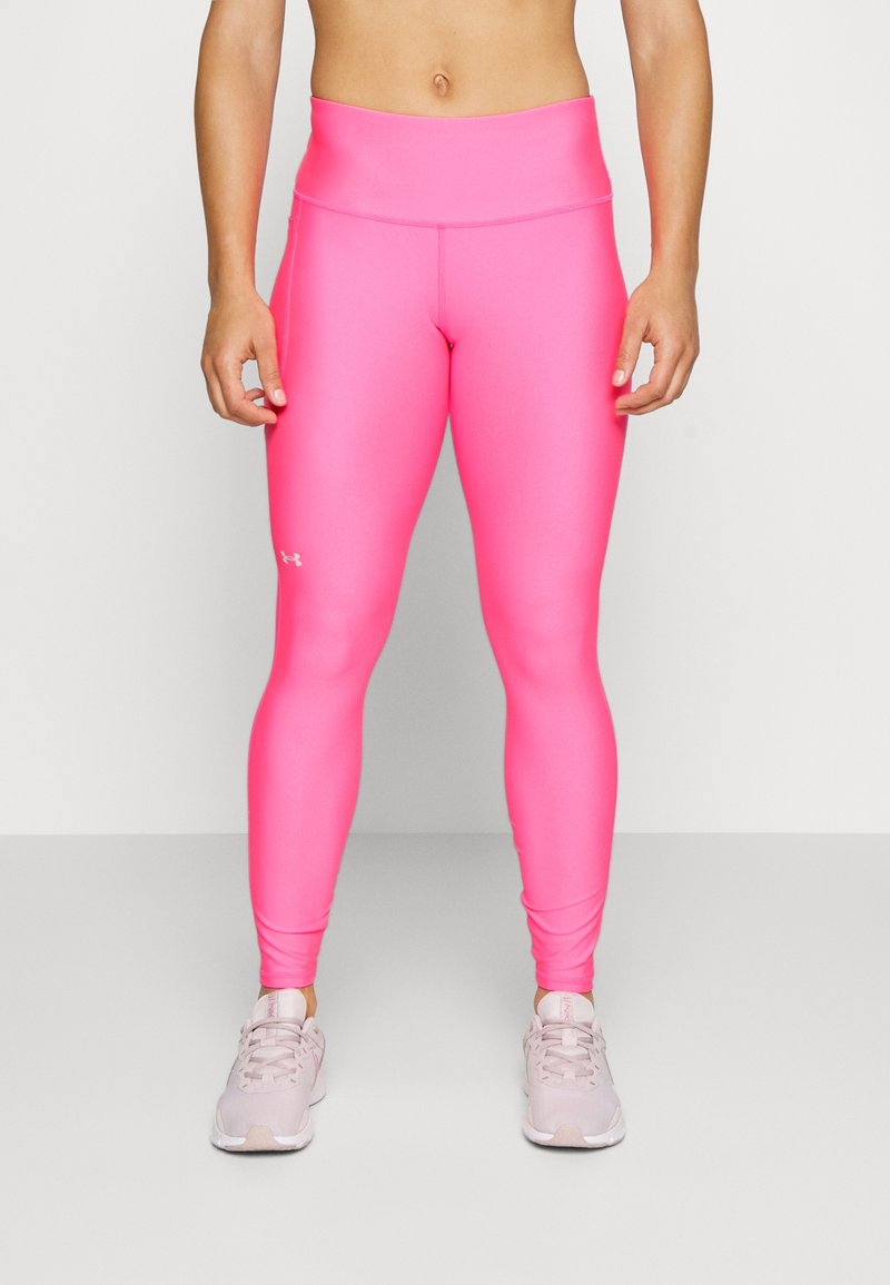 Růžové legíny s vysokým pasem vyrobené z elastického materiálu, s hladkou texturou a tvarovaným střihem. Logo umístěné na dolní části nohy.