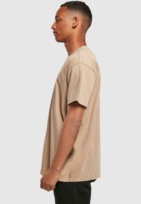 Beige kortærmet t-shirt med en afslappet pasform, lavet af blød bomuld. Har en rund halsudskæring og et enkelt design uden mønstre eller logoer.