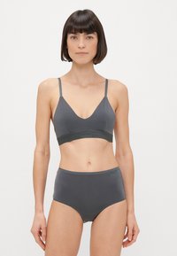 Szürke melltartó és magas derekú bugyi szett, sima anyagból készült. A melltartón vékony pántok és logós pánt található; a bugyin minimális varrás és logó részlet van.