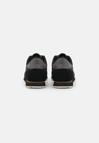Black athletic shoes featuring a suede upper, textured gray accents, white speckled outsole, and a padded collar for comfort.
