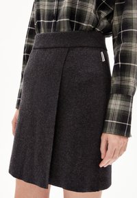 Gonna grigia scura, lunga fino al ginocchio, con una texture liscia e una larga cintura elastica; presenta una piega frontale netta per dettagli.