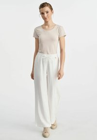 Jasnobeżowa dopasowana koszulka i luźne białe spodnie lniane z elastycznym pasem i sznurkiem. Miękka tekstura, minimalistyczny design.