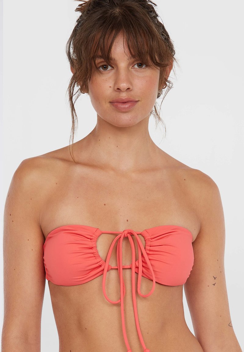 Korall színű bandeau bikini felső, ráncolt textúrával, kulcslyuk kivágással és állítható elülső megkötővel. Simító anyag, további fémalkatrészek nélkül.