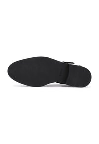 Semelle de chaussure noire avec une finition lisse, légère texture sur les bords et marquage en relief. Forme effilée pour un design ajusté.