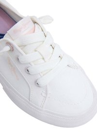 Sneaker bianca in tela con punta rotonda, parte anteriore con lacci e suola in gomma. Presenta il logo sulla linguetta e sui fori per i lacci. Tessuto liscio, design minimalista.