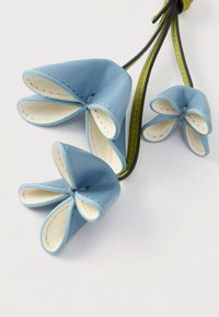 Sinine nahast lillekujundus kolme kroonlehtega, millel on kreemika sisetextuuriga ja rohelised aktsendid mustal varrel.