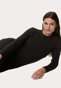 Maglietta nera a maniche lunghe realizzata in un tessuto morbido e elasticizzato. Presenta un colletto rotondo e una forma aderente, con dettagli lisci e senza cuciture.