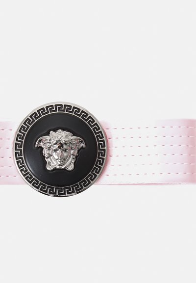 Rozā lentas josta, kurai ir apaļa melna medaļa ar sudraba Medūzas galvu, ko akcentē Grieķu atslēgas dizains ap malas.