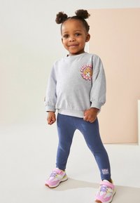 Szary sweter z grafiką lwa, niebieskie legginsy i różowe trampki z białymi akcentami. Prosty design i miękkie tkaniny dla komfortu.