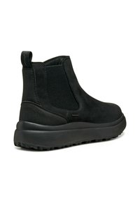 Bottines noires en suède et élastique, dotées d'une épaisse semelle en caoutchouc, de côtés texturés et d'une languette à l'arrière pour faciliter l'enfilage.