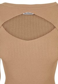 Haut beige à côtes avec un décolleté arrondi et un détail découpé dans le dos. Texture douce, design ajusté. L'étiquette indique qu'il a été fabriqué au Bangladesh.