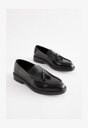 Sorte læder loafers med kvastdetalje, synlige sømme og en lav blokhæl. Glat tekstur med en poleret finish.