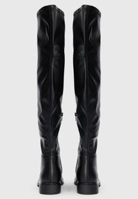 Botas negras hasta la rodilla, hechas de cuero suave, con un diseño ajustado, costuras sutiles y cremalleras plateadas en los laterales de los tobillos.