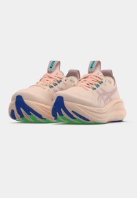 Chaussures de course rose clair avec une tige texturée, des accents bleus et verts sur la semelle, et un col rembourré. Boucles de lacets multicolores.