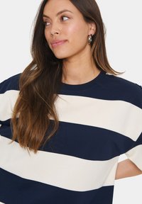 Navy and cream striped short-sleeve shirt with a round neckline. Made of soft fabric, featuring a relaxed fit and slight drop shoulder design.