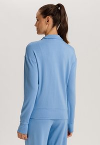 Ljusblå sweatshirt med långa ärmar, en mjuk textur och en avslappnad passform med ribbad nederkant och muddar.