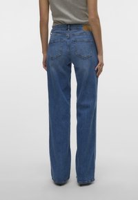 Jeans de mezclilla azul de talle alto con un corte relajado, cinco bolsillos y una etiqueta de cuero en la parte posterior de la cinturilla.