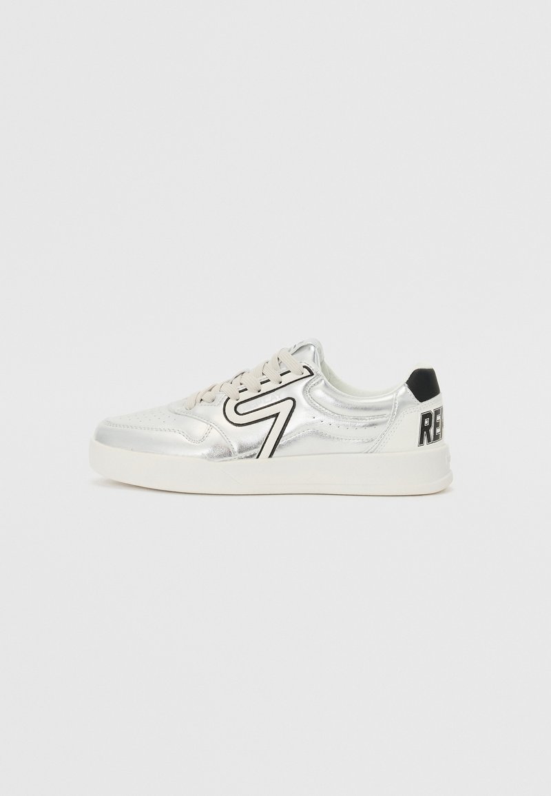 Sølvmetalliske sneakers med en glatt tekstur, som har svarte detaljer og en stor "RE"-logo på hælen. Sko med snøring.