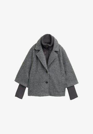 Cappotto grigio testurizzato con colletto, grandi bottoni e maniche corte. Presenta uno strato interno scuro con un design trapuntato.