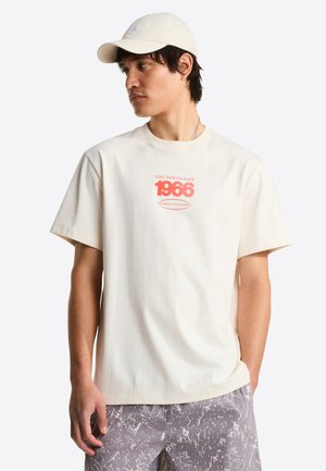 Crèmekleurig katoenen t-shirt met een ronde hals, korte mouwen en roze grafische tekst "THE NORTH FACE 1966" op de voorkant.
