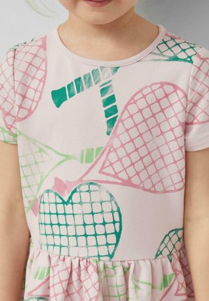 Kind draagt een lichtroze jurk met korte mouwen, voorzien van groene en roze abstracte hart- en netpatronen.