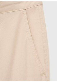 Béžové kalhoty z látky s boční kapsou. Hladká struktura s viditelným prošíváním a čistým, jednoduchým designem.