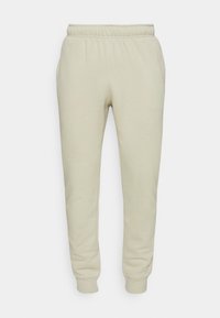 Ljusbeige sweatpants med elastisk midja, smalnande ben och ribbade muddar. Tillverkade av mjukt, texturerat tyg. Inga synliga fickor.