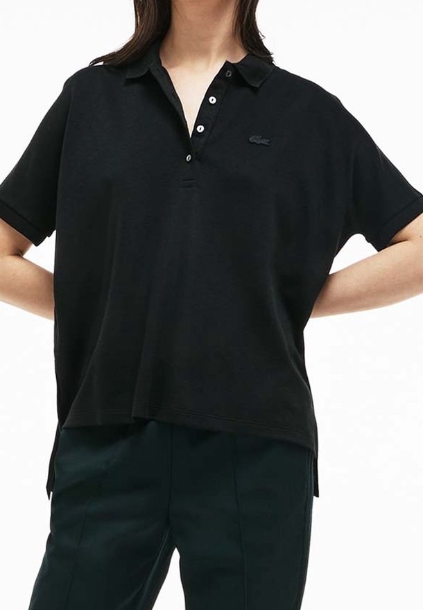 Svart polo skjorta med korta ärmar, utrustad med en tre-knappsslå och en liten broderad logga på bröstet. Tillverkad av texturerat tyg.