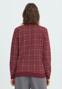 Sudadera burdeos con un diseño estampado que presenta pequeñas estrellas y círculos. Puños y dobladillo de canalé, tejido texturizado. Se muestra la vista trasera.