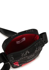 Borsa in nylon nera con interno rosso, dotata di chiusura con zip, tracolla regolabile e motivo con logo ripetuto all'esterno.