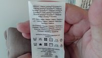 Etichetta del capo che mostra la composizione del tessuto (viscosa, nylon, elastan) e le istruzioni per il lavaggio, inclusi lavaggi delicati a freddo in lavatrice, senza candeggina, no asciugatrice, asciugatura all'aria, stiratura a bassa temperatura.