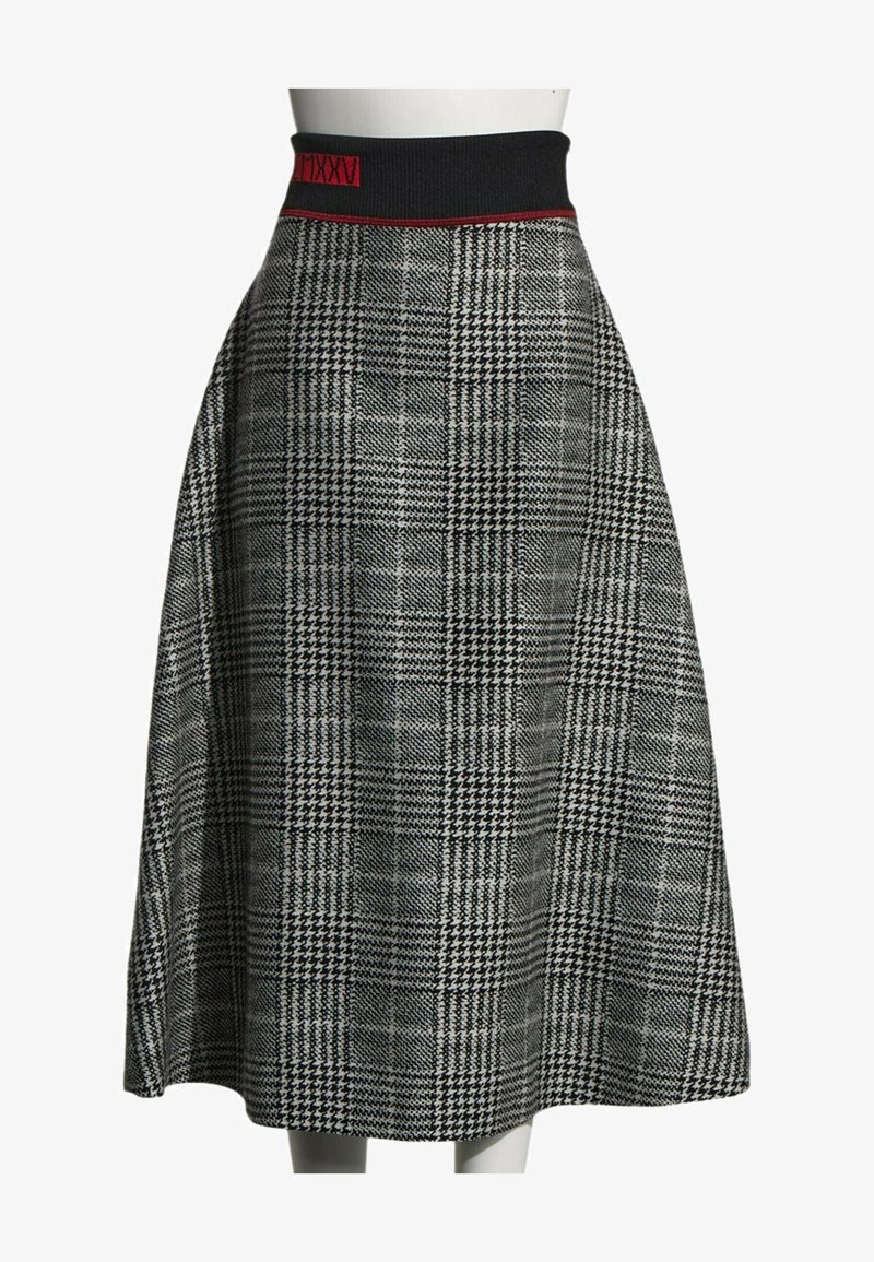 Jupe midi à taille haute à carreaux pied-de-poule noir et blanc avec une ceinture élastique noire ornée d'un détail en chiffres romains rouges.