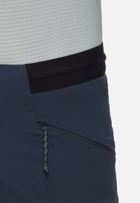 Marina softshellbyxor med en kontrasterande svart elastisk midja och sidoficka med dragkedja och snodd. Slät textur, lättviktsmaterial.