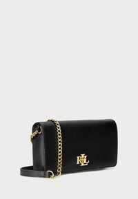 Borsa a tracolla in pelle nera con una tracolla in catena dorata, forma rettangolare, con un accento del logo dorato sul fronte. Texture liscia.