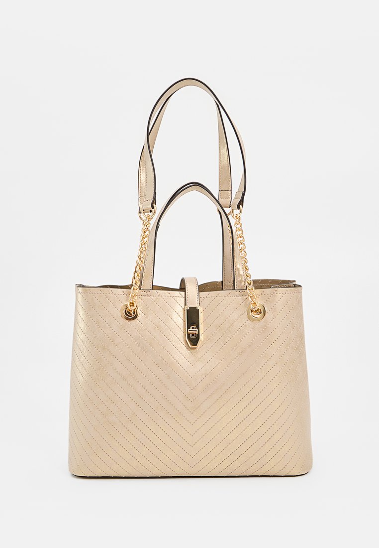 Bolso de cuero beige con patrón de chevron acolchado, asas de cadena dorada y cierre central con broche dorado.