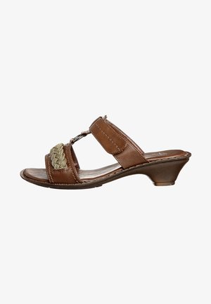 Sandalia deslizante de cuero marrón con un tacón bajo, que presenta acentos trenzados en verde y correas ajustables. Textura suave y diseño abierto.