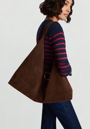 Borsa tote in pelle scamosciata marrone con forma triangolare, caratterizzata da un grande dettaglio ad anello in metallo dorato e una texture morbida.