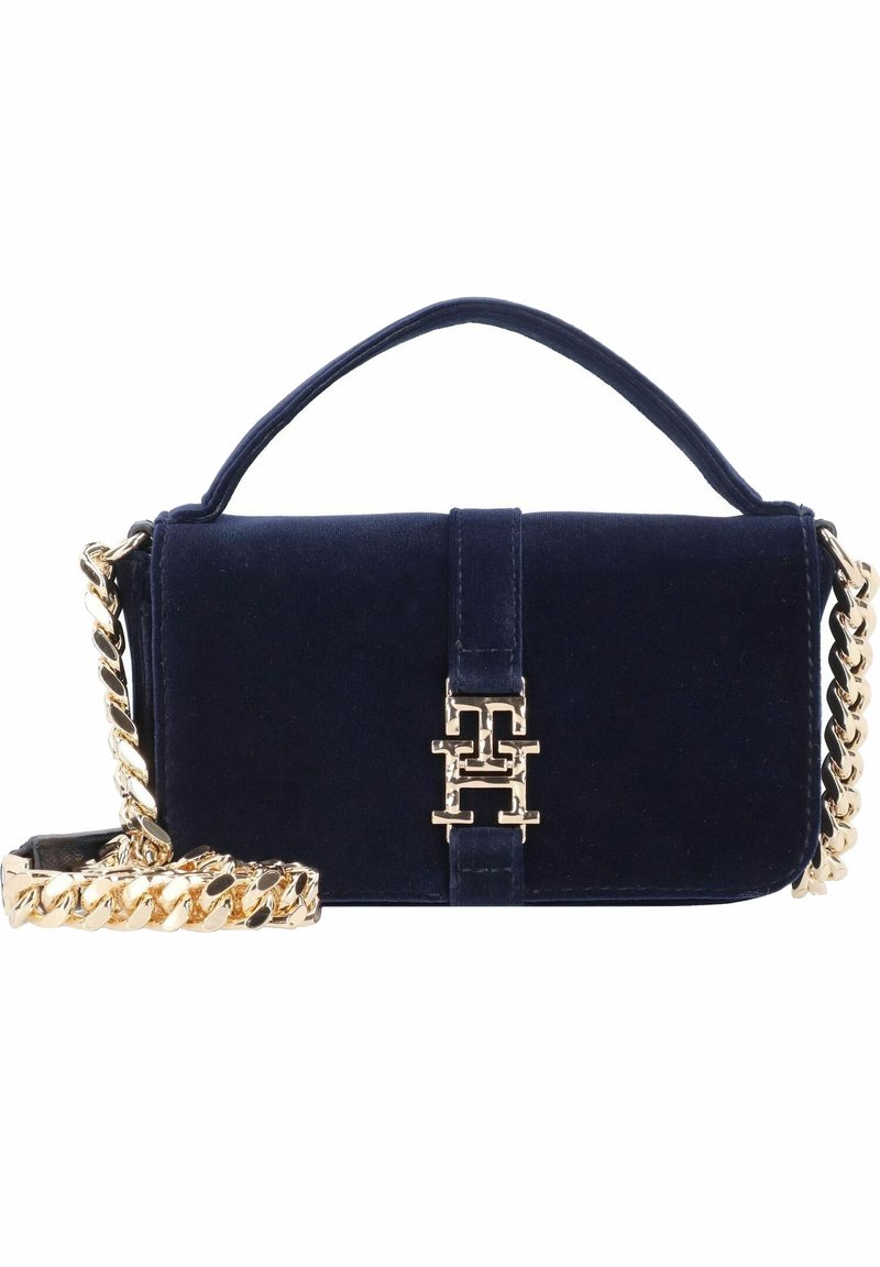 Sac à main en velours bleu marine avec bandoulière chaîne dorée et fermoir en métal doré présentant les lettres entrelacées T et H.