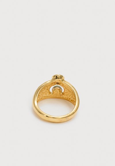 Χρυσό δαχτυλίδι με υφή, με ανυψωμένο οβάλ επάνω μέρος και μικρή ασημένια λεπτομέρεια σε σχήμα ημισελήνου μέσα στην μπάντα.