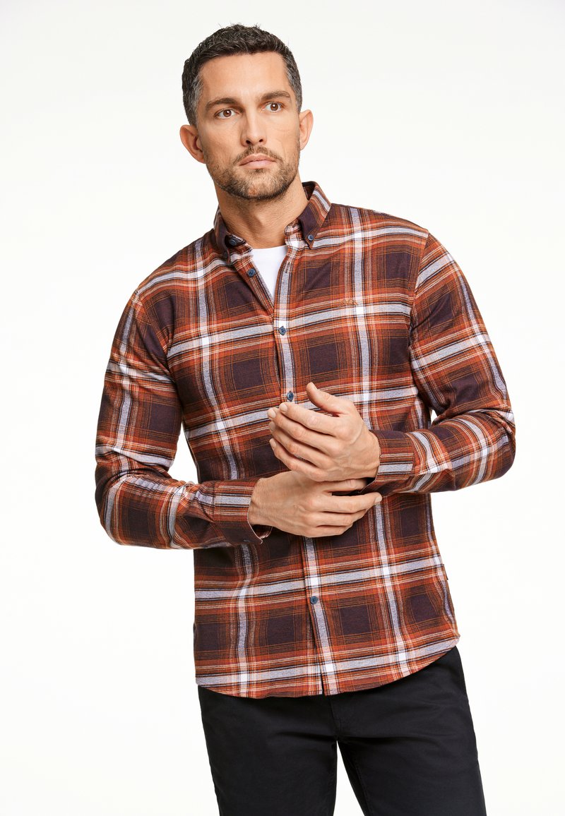 Camicia a quadri marrone e arancione in tessuto di cotone, con colletto button-down e dettagli in metallo, abbinata a pantaloni scuri.