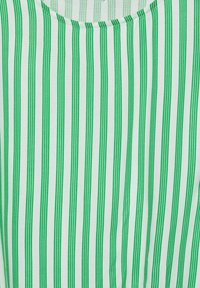 Topp i bomull med rund halsringning, med vertikala gröna och vita ränder. Mjuk textur med jämnt fördelade ränder och en lätt känsla.