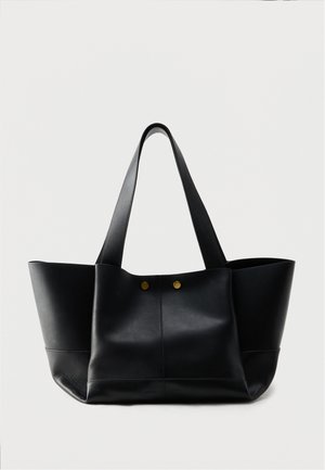 Black leather tote bag with two wide handles and two gold metal studs on the front, displayed against a plain white background.