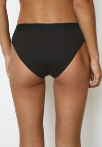 Zwarte geribbelde bikini onderkant met een gladde tailleband, een middelhoge pasvorm en minimale bedekking, die een strakke fit en schone lijnen laat zien.