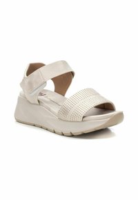 Sandalias de cuña beige con parte alta perforada, tira ancha en el tobillo y plantilla acolchada. Suela de goma flexible para mayor comodidad y agarre.