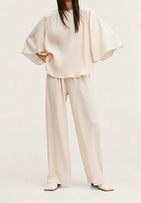 Beige ribbet loungewear sæt med en løstsiddende, kortærmet top og brede bukser. Glat tekstur med en afslappet silhuet.