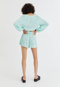 Ensemble composé de deux pièces floral vert clair, comprenant un top court à manches longues et un short taille haute, fabriqué dans un tissu doux et texturé.